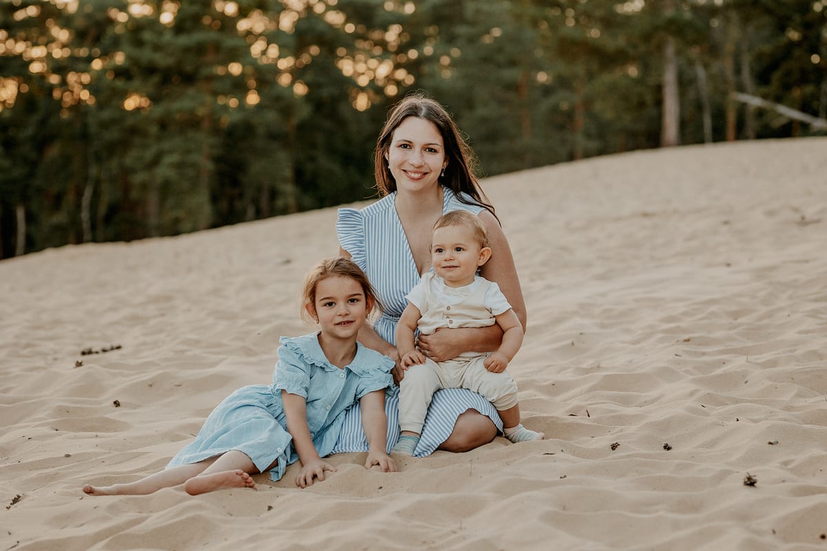Fotografka Nikolka Světinská se svými dětmi sedí na písku u borového lesa ve večerním světle
