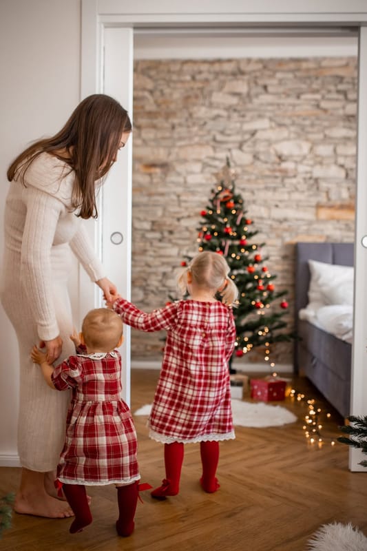 Maminka s dvěma dcerami v kostkovaných šatech jde k vánočnímu stromečku